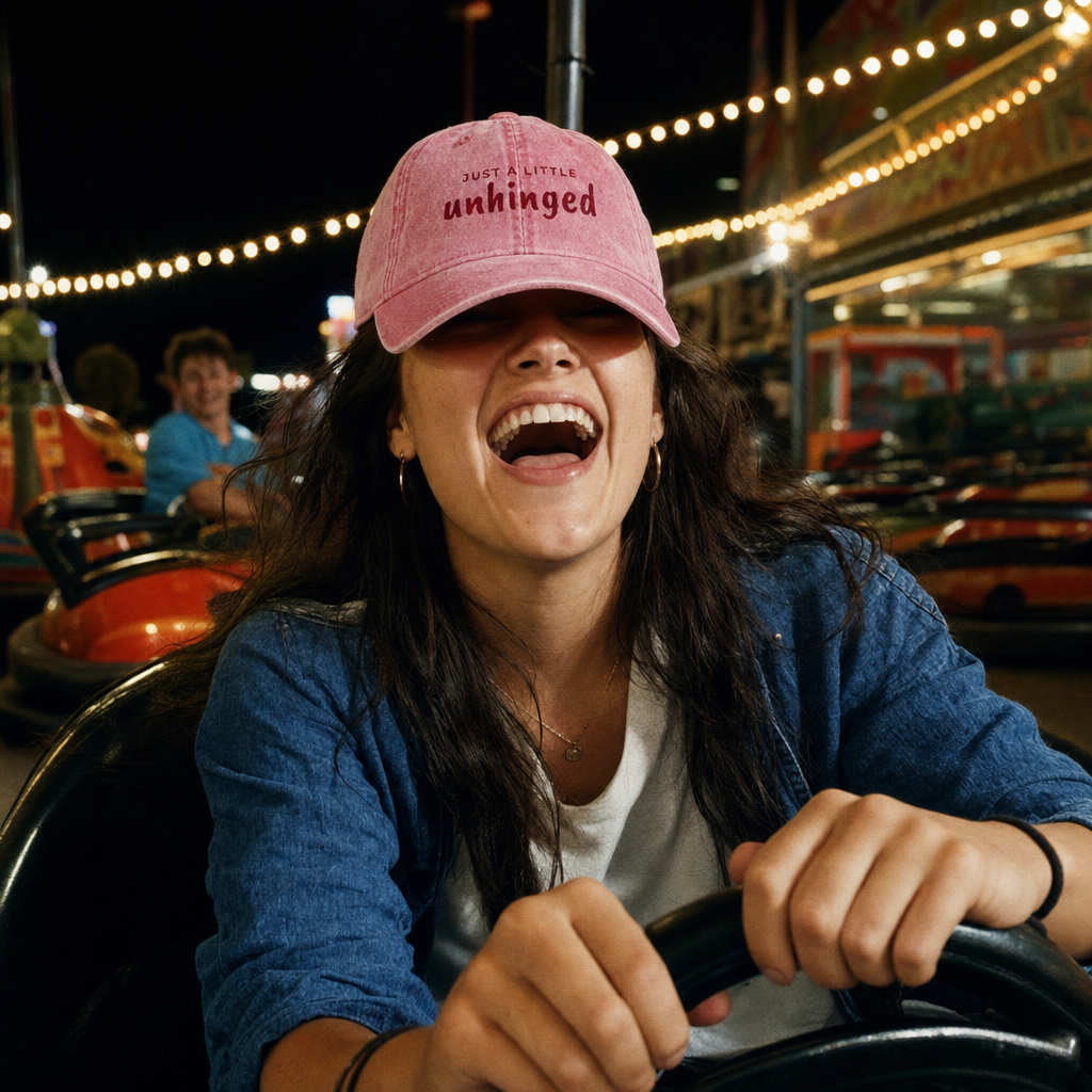 Pink vintage cap embroidered “just a little unhinged” in maroon, worn on the dodgems at a funfair
