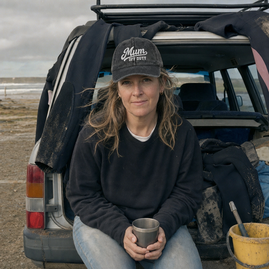Washed black vintage cap embroidered “Mum Off Duty” in white script, worn at a beach car park